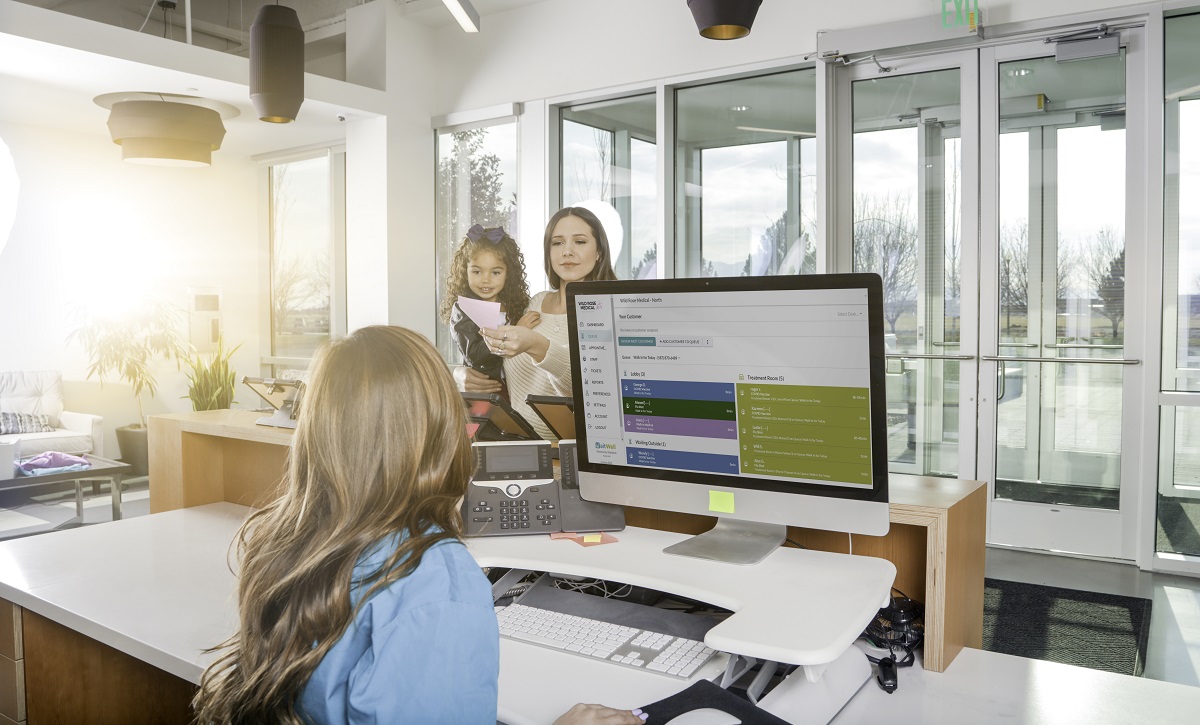woman with child at the medical office waiting room handing paper to receptionist