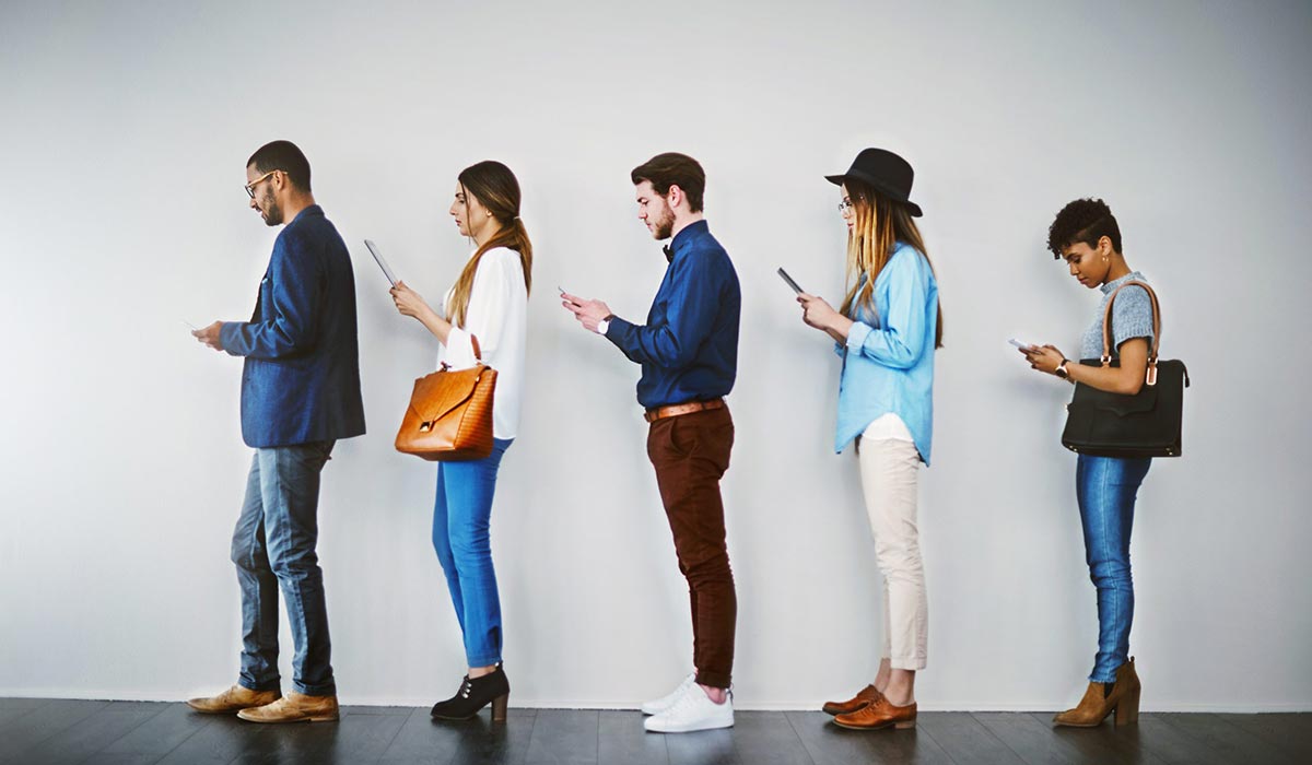 five people waiting in line against white wall