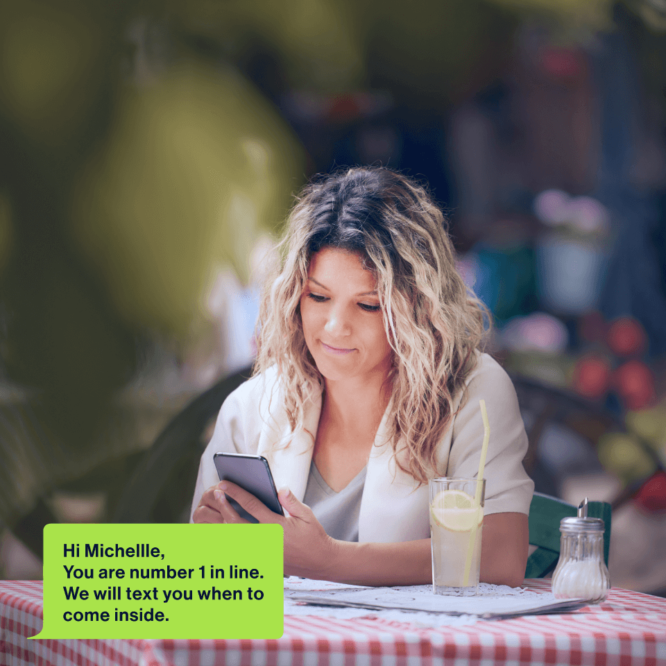 Woman at cafe receiving SMS queue reminder
